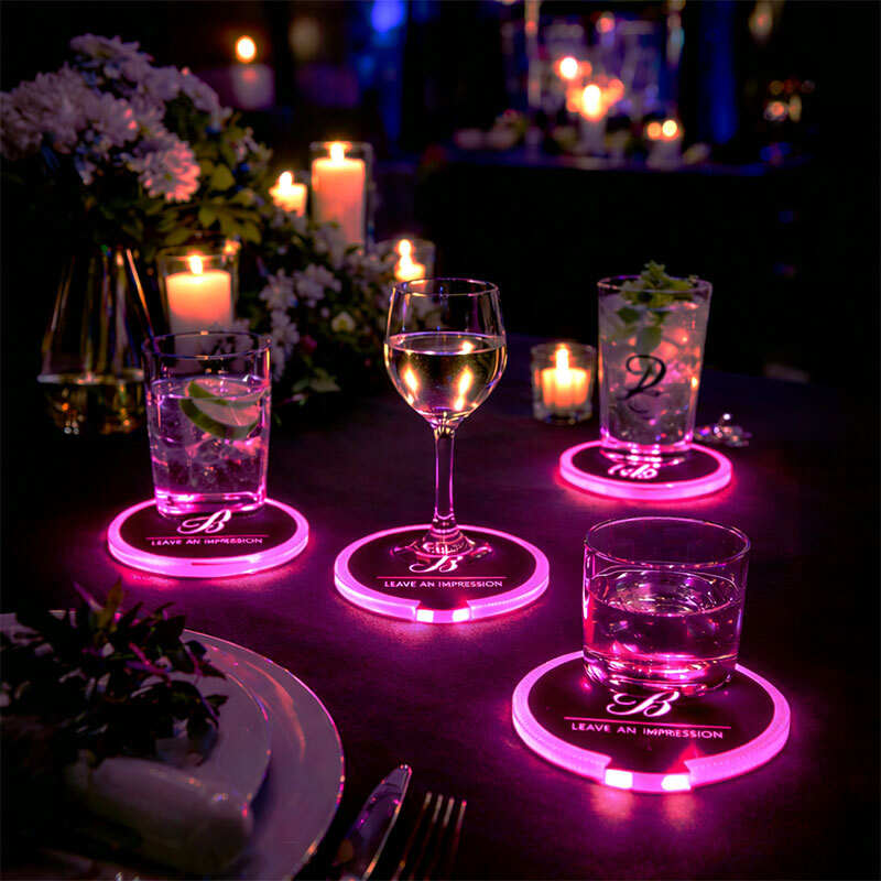Glowing pink light up drink coasters featuring a custom logo arranged on a decorated dinner table at an evening event