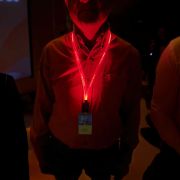 A man at a conference wearing a red LED lanyard that illuminates a custom logo