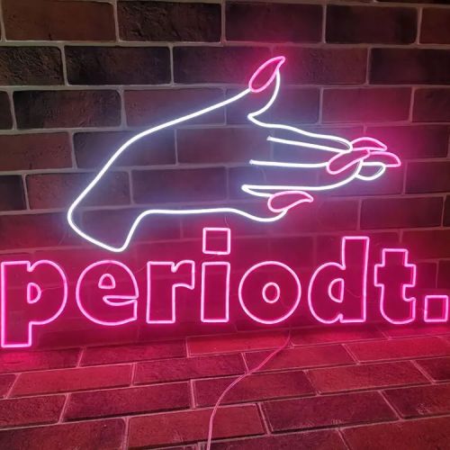 LED neon sign against brick background with white hand and pink fingernails and the word periodt. lighting up in hot pink below