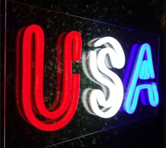 Side angle of clear acrylic LED neon sign with USA letters lighting up red white and blue