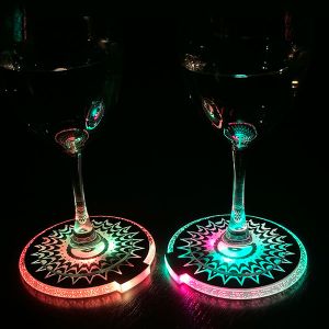 two wine glasses sitting on top of LED drink coasters shining bright rainbow colors in the dark