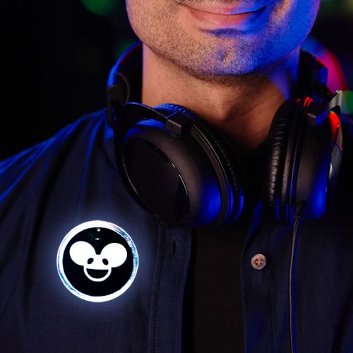 Close up of man wearing big headphones around their neck with a custom DJ inspired LED pin on his jacket, lighting up bright white
