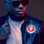 African American male wearing black leather jacket with custom LED pin lighting up bright red and white on his jacket