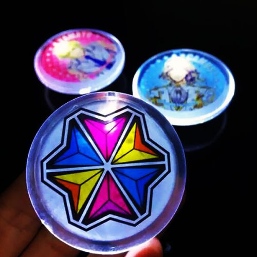One multicolor printed logo LED pin in foreground with two other colorful LED pins in the background, each lighting up white