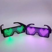 Two pairs of LED sunglasses lit up with hearts, one in green LEDs the other in pink LEDs