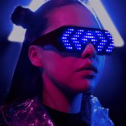 Cyber looking woman in front of LED light wearing light up LED animated sunglasses in a chevron pattern glowing blue