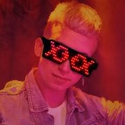 Blonde haired man wearing jean jacket and LED sunglasses glowing a red fish pattern on each lens