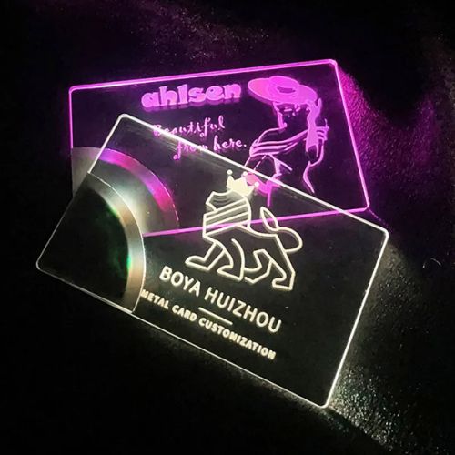 Two different designs of clear acrylic LED business cards, one lighting up white the other bright pink