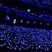 crowd waving LED remote wands in air that are synchronized and changing colors from blue to pink