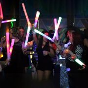 Big group of people at special event dancing with LED foam sticks