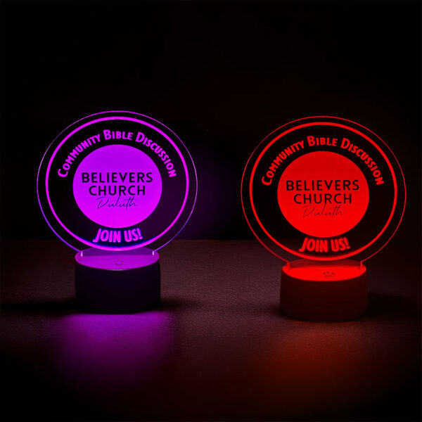Red and purple illuminated circular table signs with lights glowing and the text "Believe Church," engraved