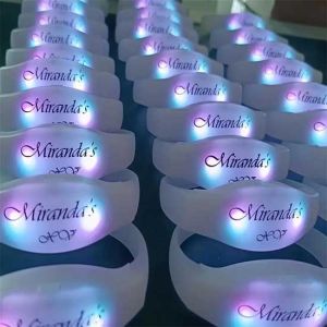 Many rows of light up bracelets glowing with custom logo for quinceanera