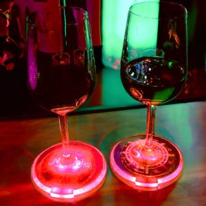 Two wine glasses on bar sitting on customized LED coasters