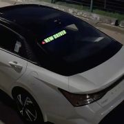 glowing new driver safety el sticker lighting up on back windshield of car