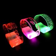 Three different designs laser engraved onto three LED wristbands, one lighting up from left to right: red, pink and green