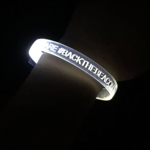 close up of led bracelet on wrist with the phrase #BackTheBeacon glowing bright white