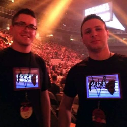 two guys wearing light up shirts in front of concert arena
