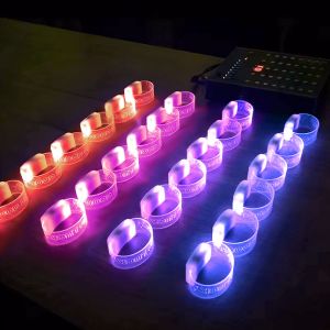 four lines of light up wristbands sitting on table with each row illuminating a different color due to the RFID remote controller to the right of the bracelets