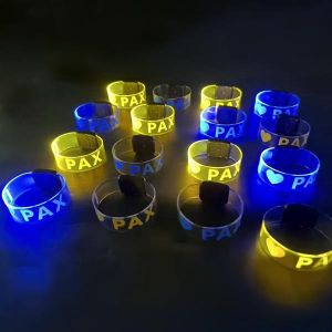 Table full of glowing blue and yellow wristbands with screen printed logo reading "I heart Pax"