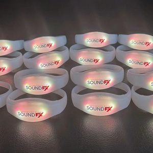 15 stacked silicone remote controlled bracelets with SoundFX logo all glowing orange lights