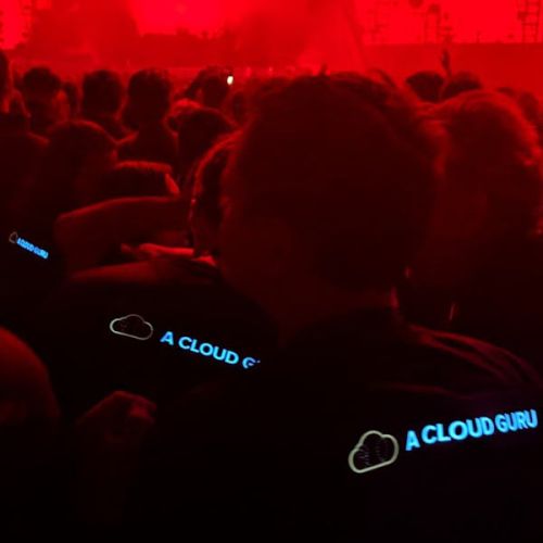 back of crowd at event with three people glowing in their custom light up shirts with cloud company logo
