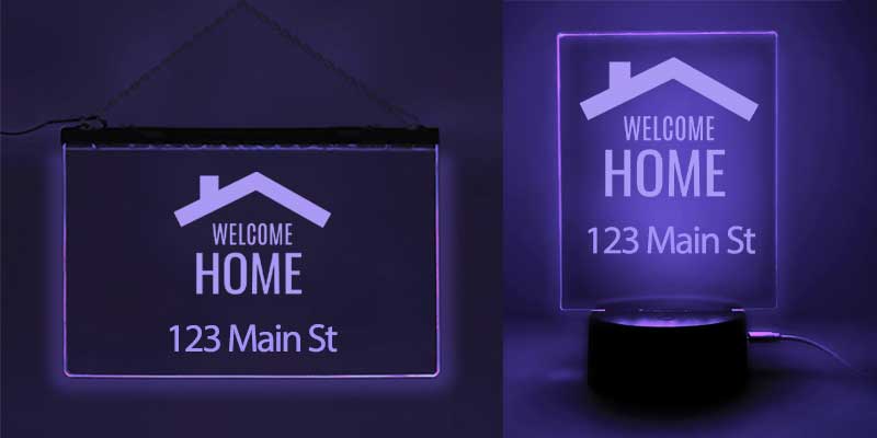 A purple light-up sign saying "Welcome Home," ideal for real estate gifts, shown alongside a table lamp.