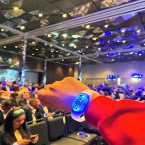 Person showing off branded led bracelet at conference in front of crowd of people wearing LED bracelets