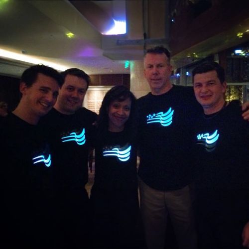group of five colleagues posing in their custom company logo light up shirt design