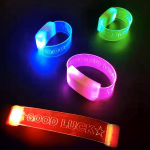 Three clasped LED wristbands in blue, green and pink placed behind an unclasped red led wristband all with "Good Luck" laser engraved onto them