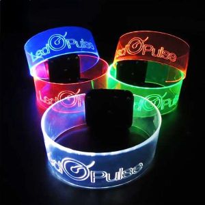 five of the same engraved design on XL LED wristbands showing logo and text, each illuminating a different rainbow color