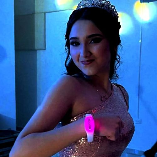 young woman in tiara and formal gown wearing a pink glowing LED bracelet