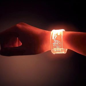 right wrist in dark room wearing a laser engraved radio station LED wristband shining bright orange
