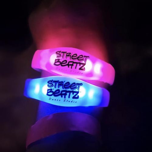 close up of wrist wearing two silicone led bracelets with "Street Beatz Dance Studio" custom logo