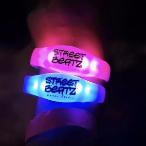 close up of wrist wearing two silicone led bracelets with "Street Beatz Dance Studio" custom logo