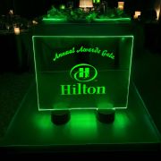 A glowing green sign at an awards gala, providing illumination in a festive event setting