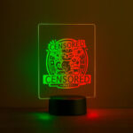 Dual-colored LED table sign with engraved ‘Censored Party’ design glowing in green and red on a table.