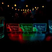 Three bright acrylic place cards with names and table numbers displayed on a table at an event