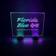 A custom engraved led table sign for Florida Blue Cross Blue Shield event glowing in green and purple neon glow