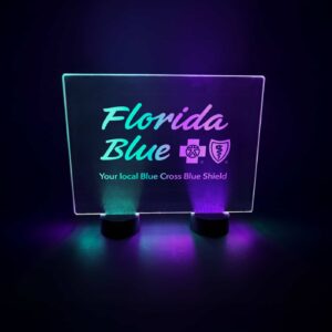 A custom engraved led table sign for Florida Blue Cross Blue Shield event glowing in green and purple neon glow
