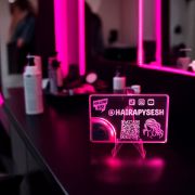 A pink illuminated acrylic business card displayed in a hair salon business