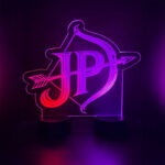 Custom JP logo engraved LED acrylic sign glowing purple and red as a centerpiece at a private celebration
