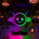 Custom double-base LED acrylic sign featuring a colorful pink and green illuminated smiley face at a gala-style table setting