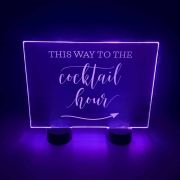 Acrylic sign with illuminated lettering pointing towards the cocktail hour
