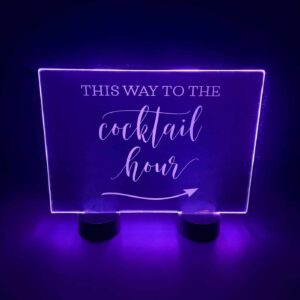 Acrylic sign with illuminated lettering pointing towards the cocktail hour
