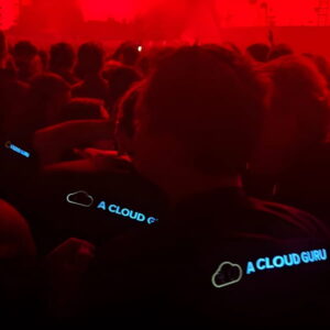 back of crowd at event with three people glowing in their custom light up shirts with cloud company logo