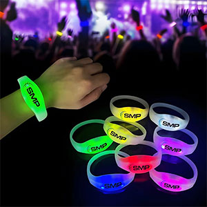 soft silicone party remote activated bracelets showing 8 colors and a crowd wearing them